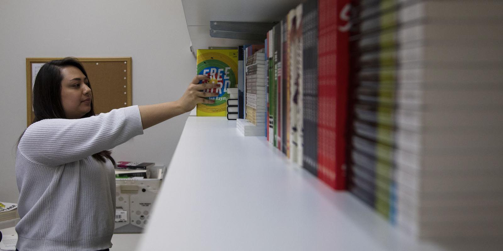 Graywolf staffer Jasmine Carlson reaching for a book